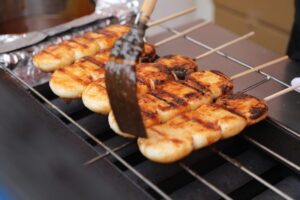 焼きまんじゅうに醤油を塗っている